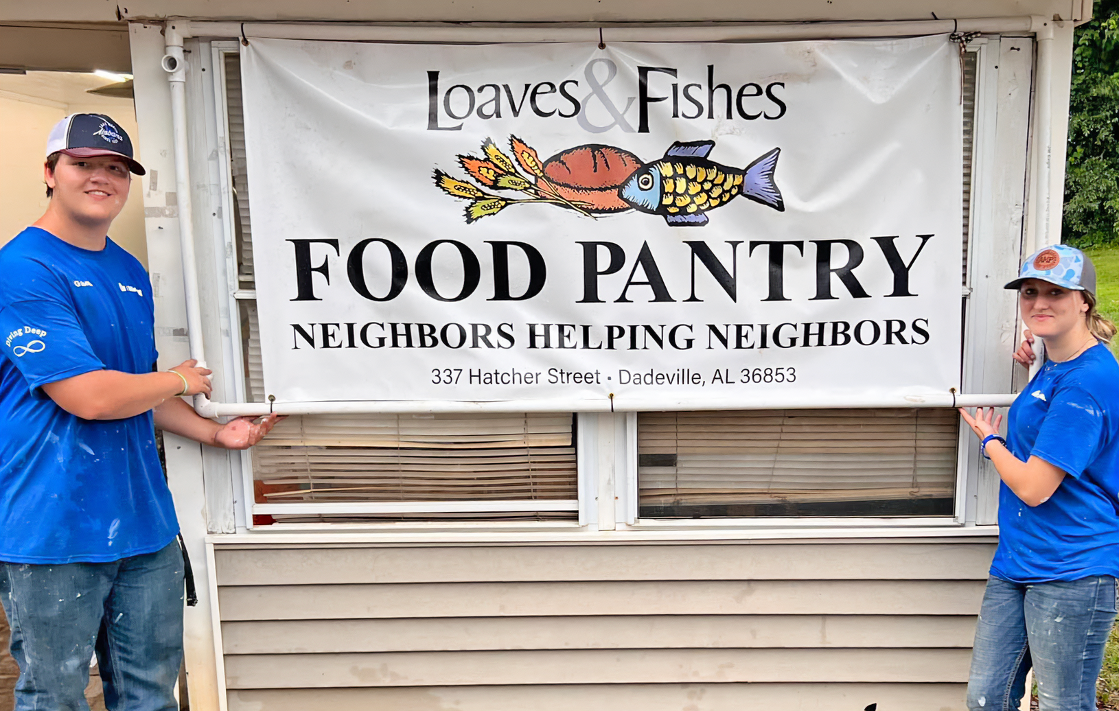 Two volunteers with the new Loaves & Fishes Food Pantry Banner